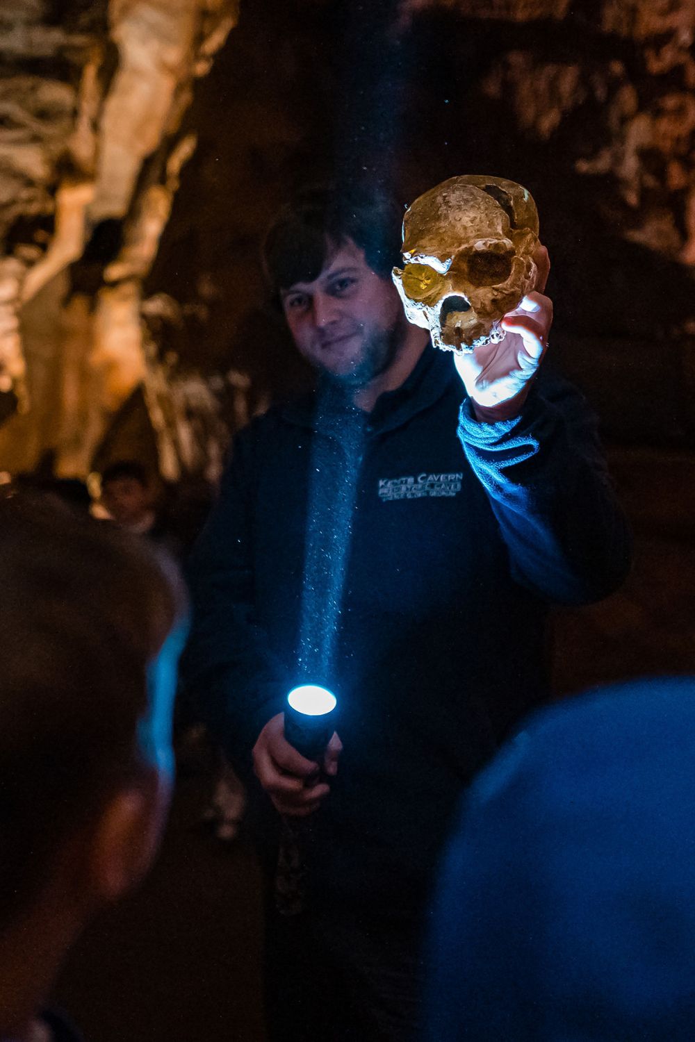Tour guide holding a Neanderthal skull in a cave | Kents Cavern, Torquay