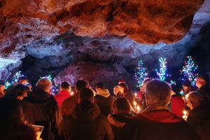 People holding candles in a cave at Carols in the Cave at Kents Cavern